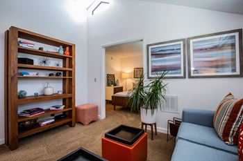 A living room with a blue couch and a wooden bookshelf.